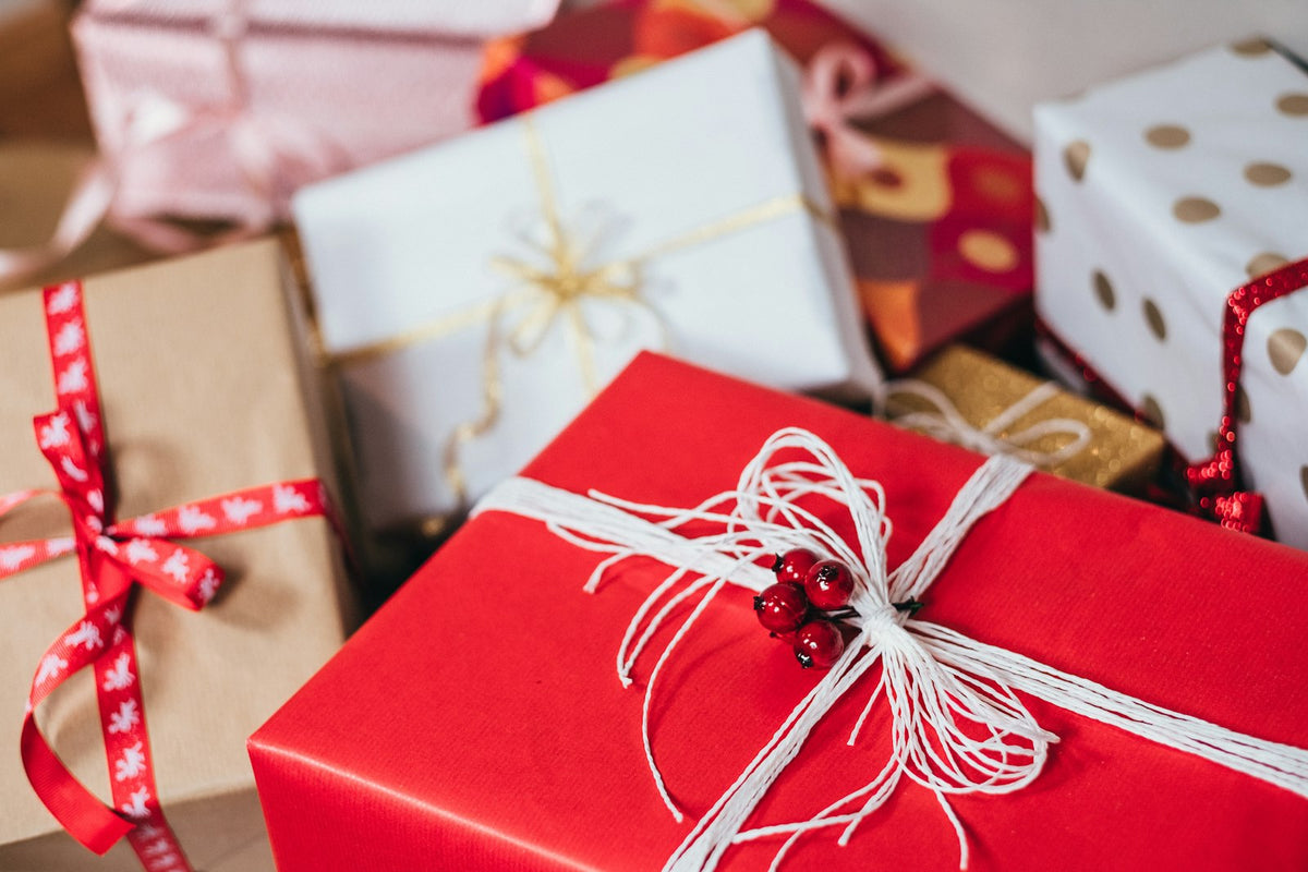 A wrapped gift with ribbon on a table beside paint brushes