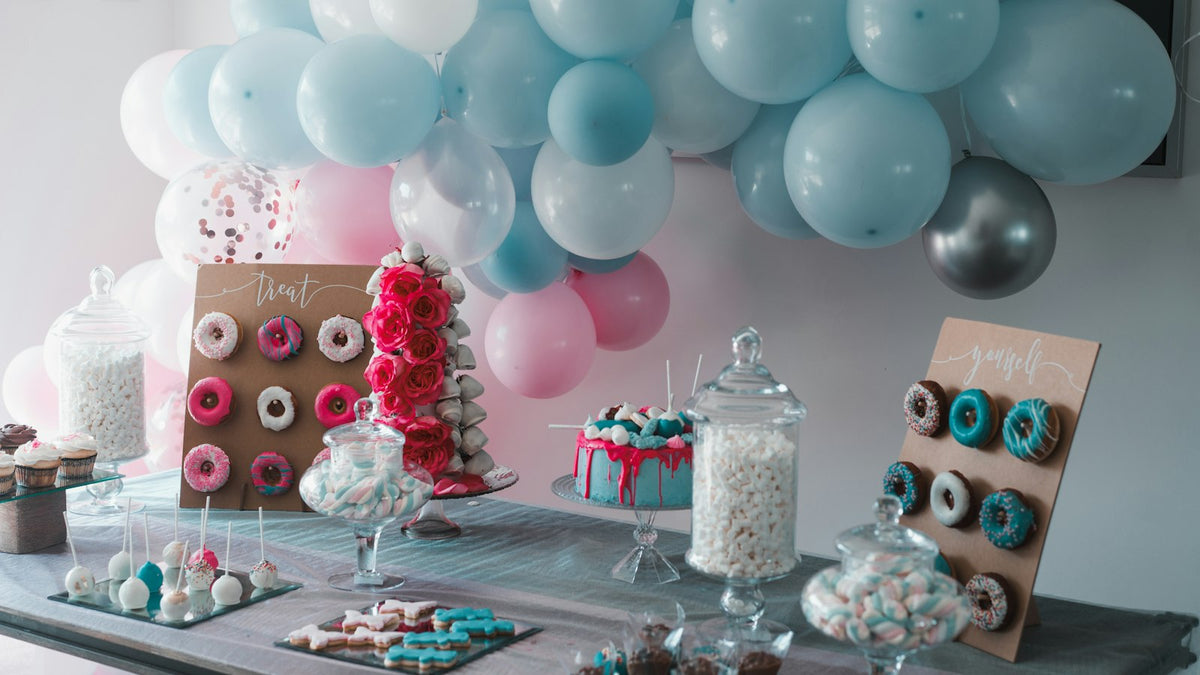 Party dessert table with pastel balloons, donut wall and sweets