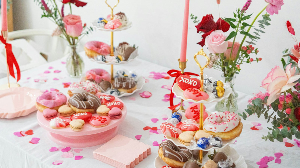 Brunch table with pink cakes, donuts, macarons and roses for a Galentine's Day party