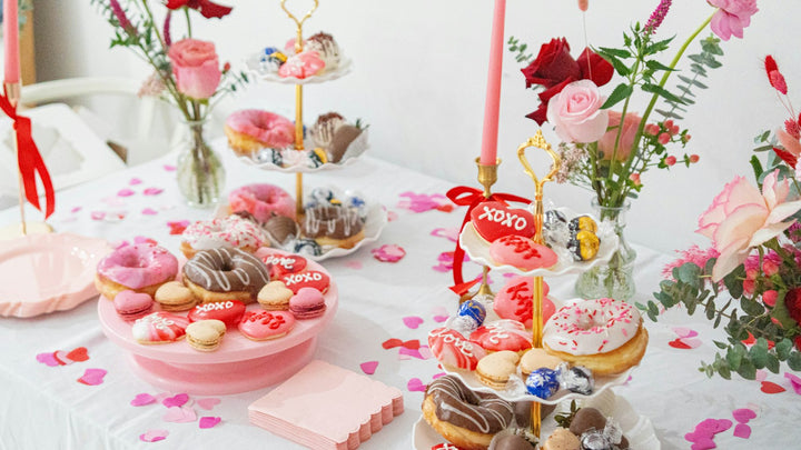 Brunch table with pink cakes, donuts, macarons and roses for a Galentine's Day party