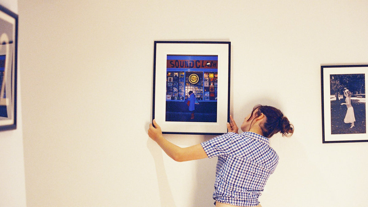 Woman hanging a framed picture on a white wall