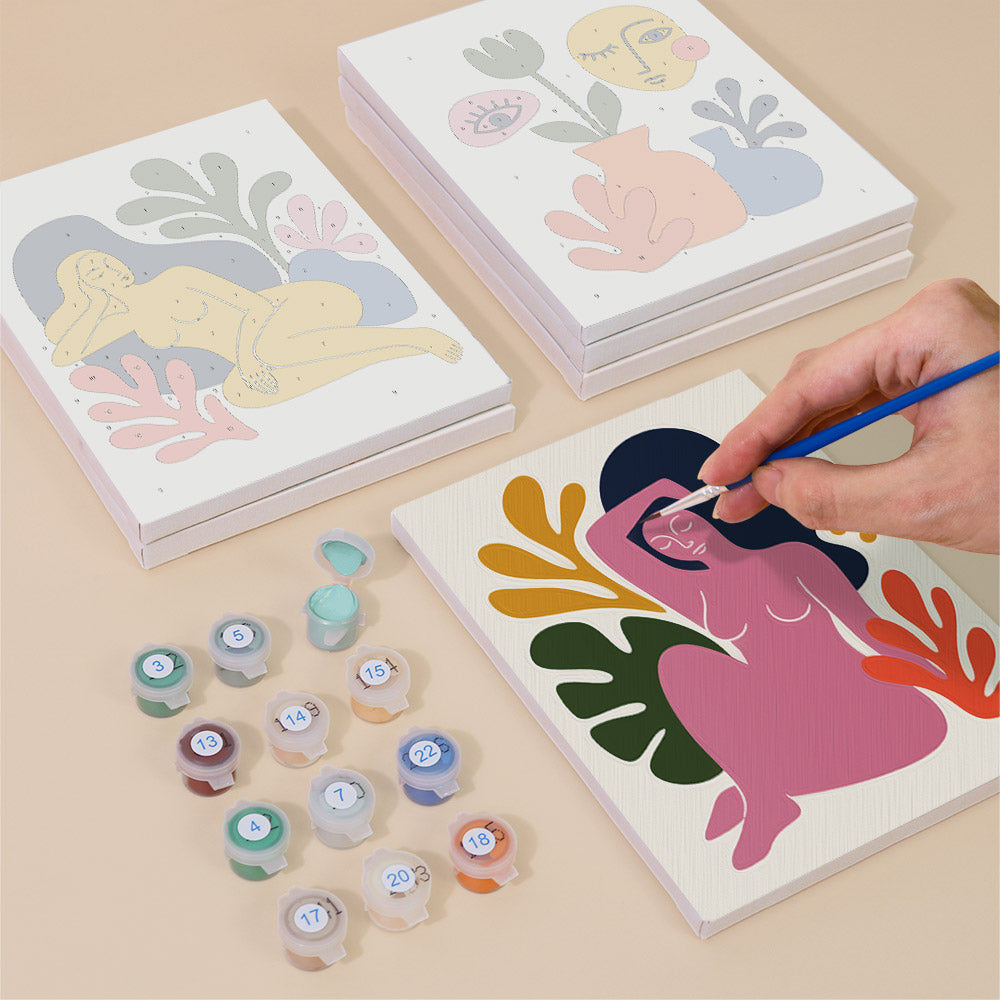 Painting one of the Abstract Figures designs next to a stack of mini canvases