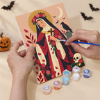 Hand holding an All Saints Night Icons mini canvas while painting the details