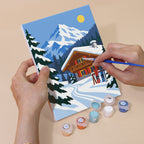Hand holding an Alpine Ski Days mini canvas while painting the details