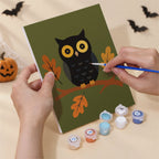 Hand holding an Autumn Apothecary mini canvas while painting the details