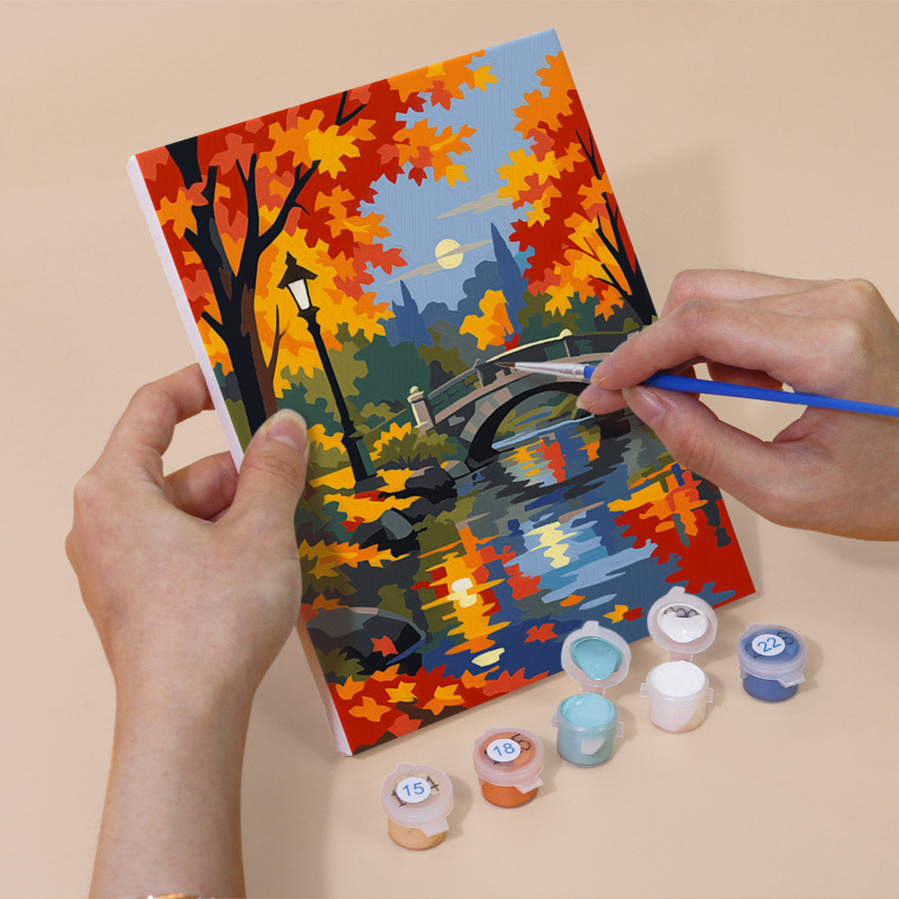 Hand holding an Autumn Rain Promenade mini canvas while painting the details