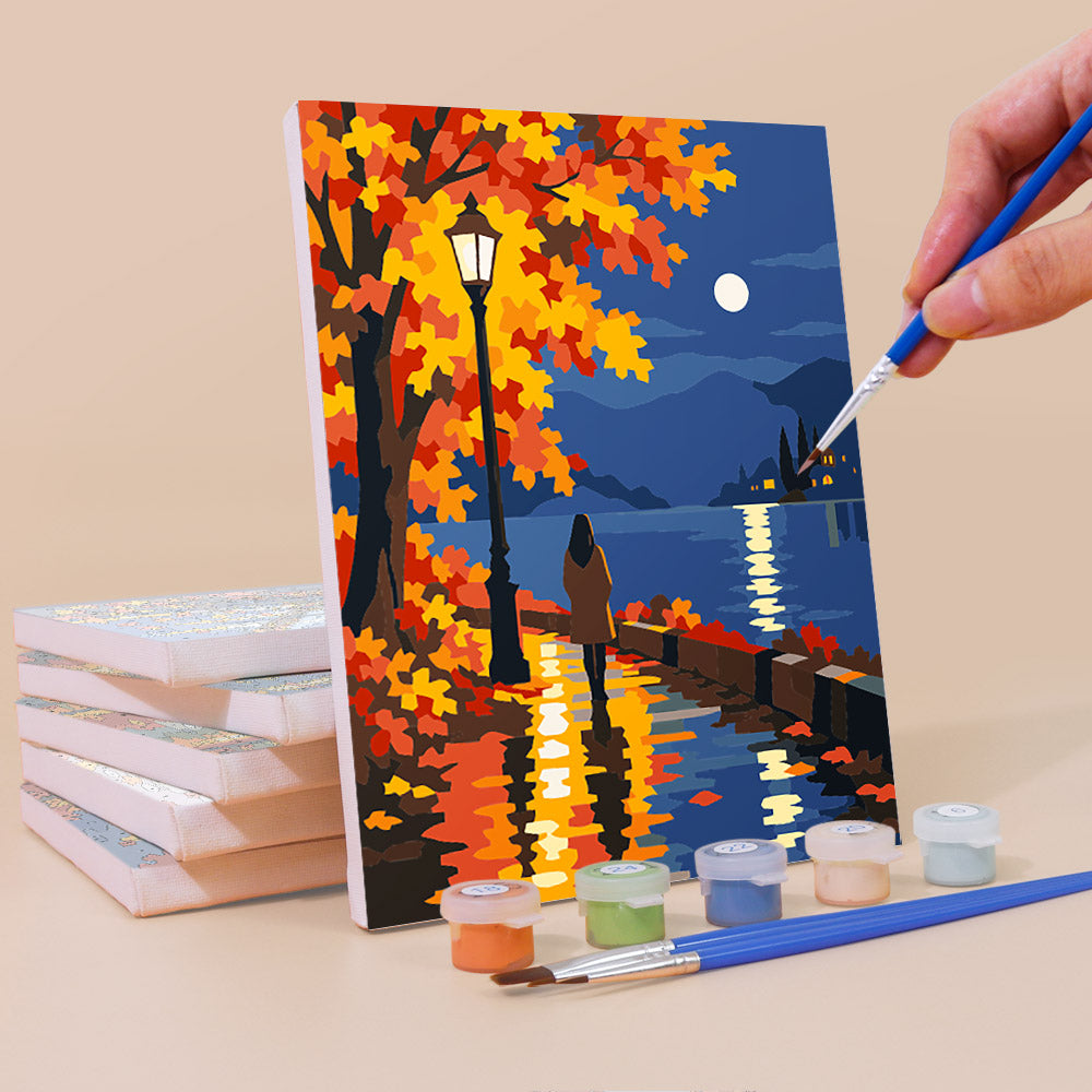 Painting an Autumn Rain Promenade mini canvas propped up beside numbered acrylic paints