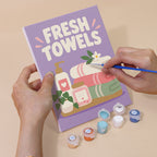 Hand holding a Bathroom Bliss mini canvas while painting the details