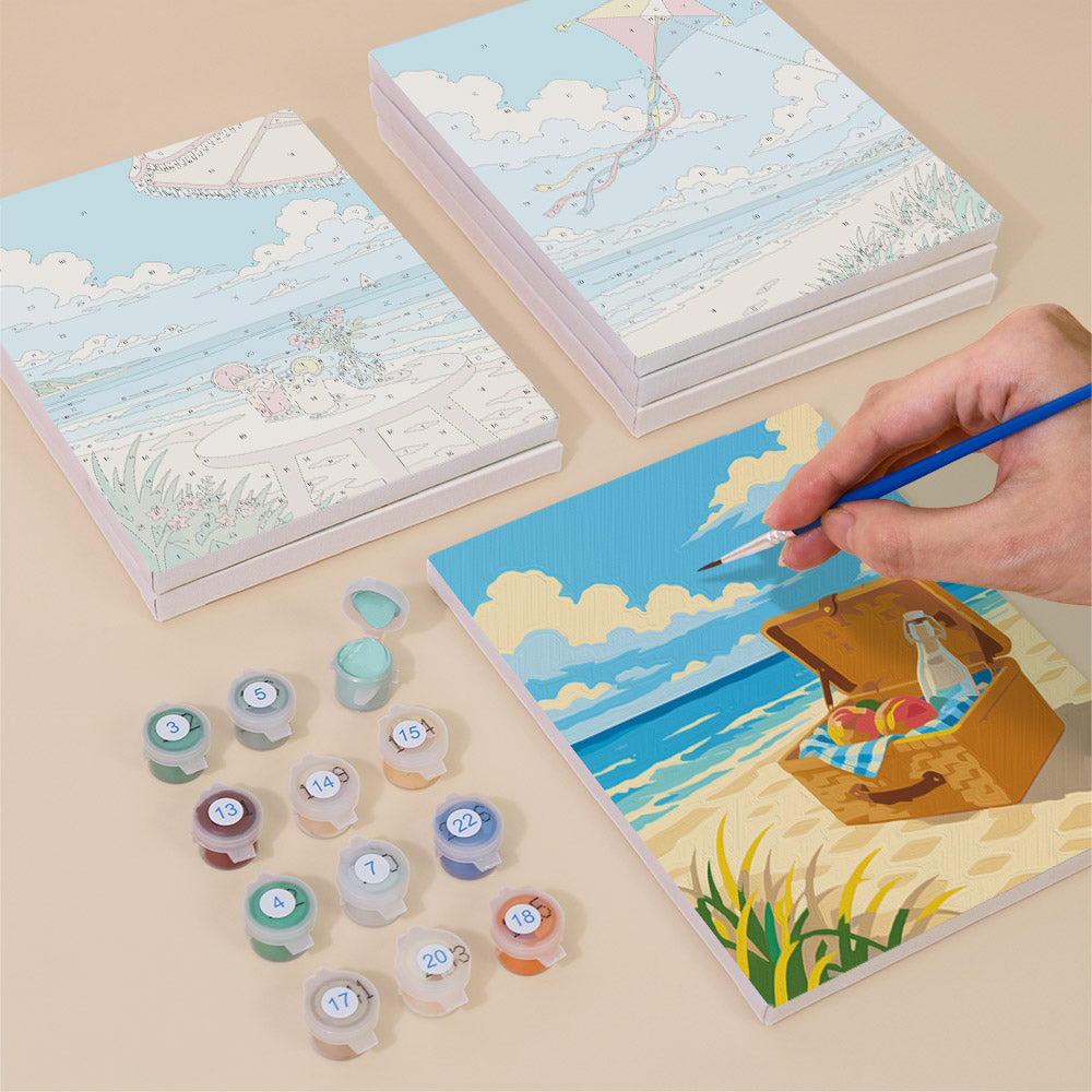 Painting one of the Beach Day designs next to a stack of mini canvases