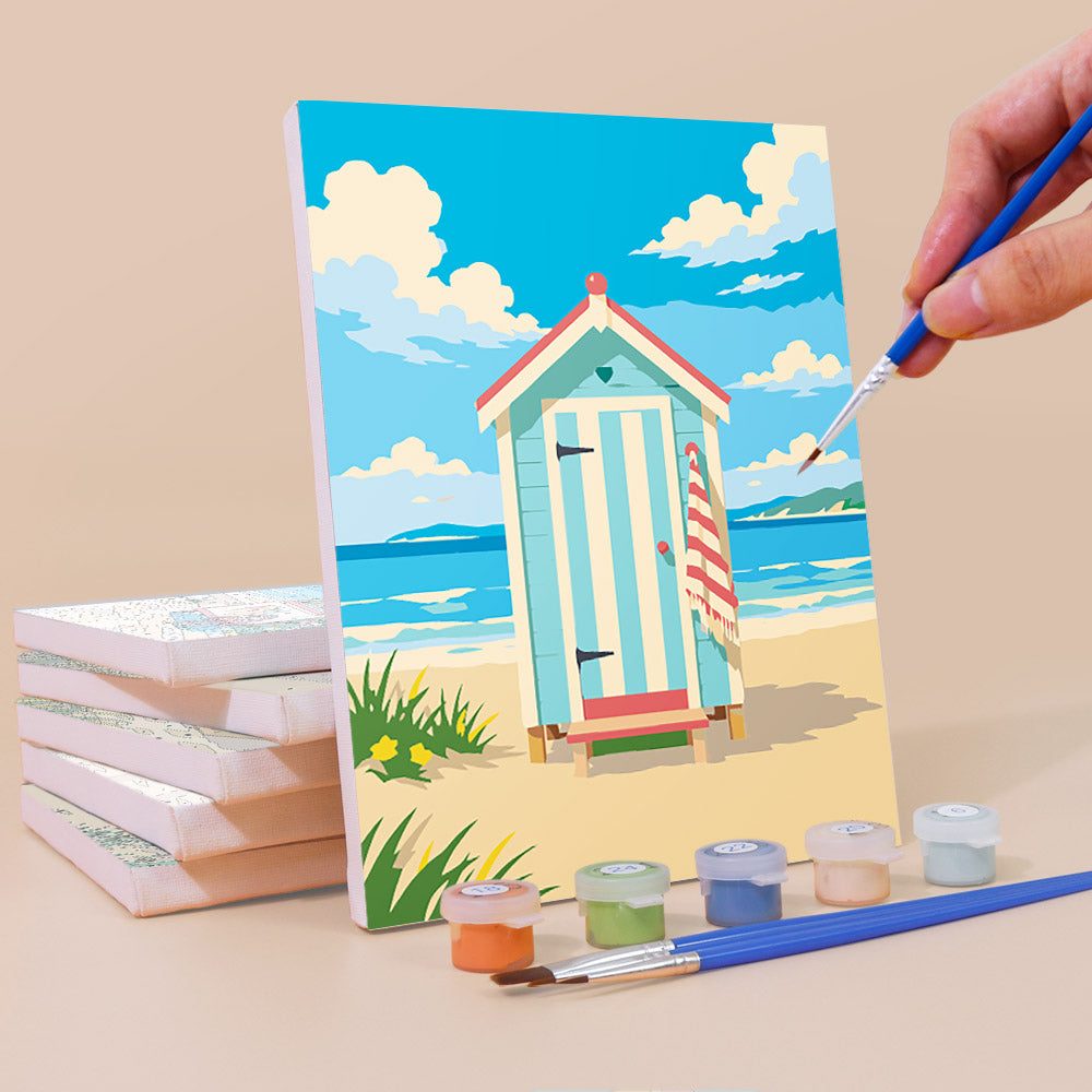 Painting a Beach Day mini canvas propped up beside numbered acrylic paints