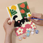 Hand holding a Black Cat Garden mini canvas while painting the details