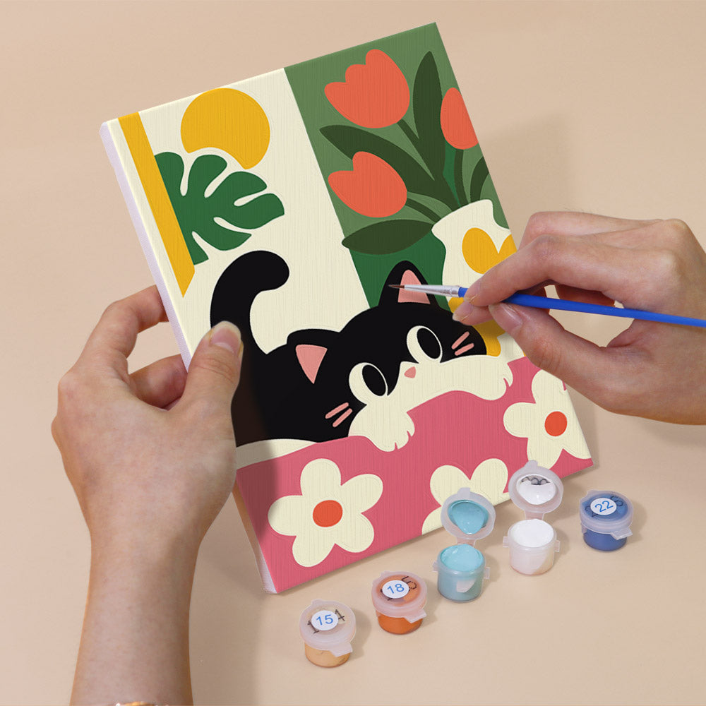 Hand holding a Black Cat Garden mini canvas while painting the details