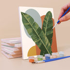 Painting a Blooming Muses mini canvas propped up beside numbered acrylic paints