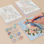Painting one of the Blossom Birds designs next to a stack of mini canvases