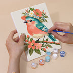 Hand holding a Blossom Birds mini canvas while painting the details