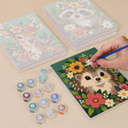 Painting one of the Blossom Critters designs next to a stack of mini canvases