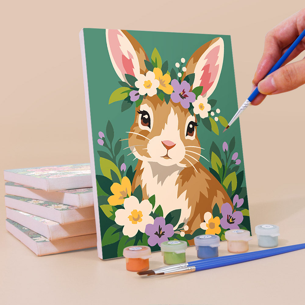 Painting a Blossom Critters mini canvas propped up beside numbered acrylic paints