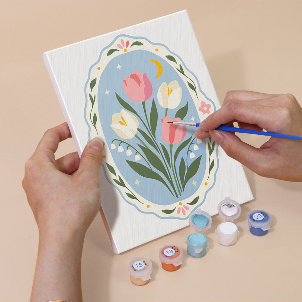 Hand holding a Blue Folk Florals mini canvas while painting the details