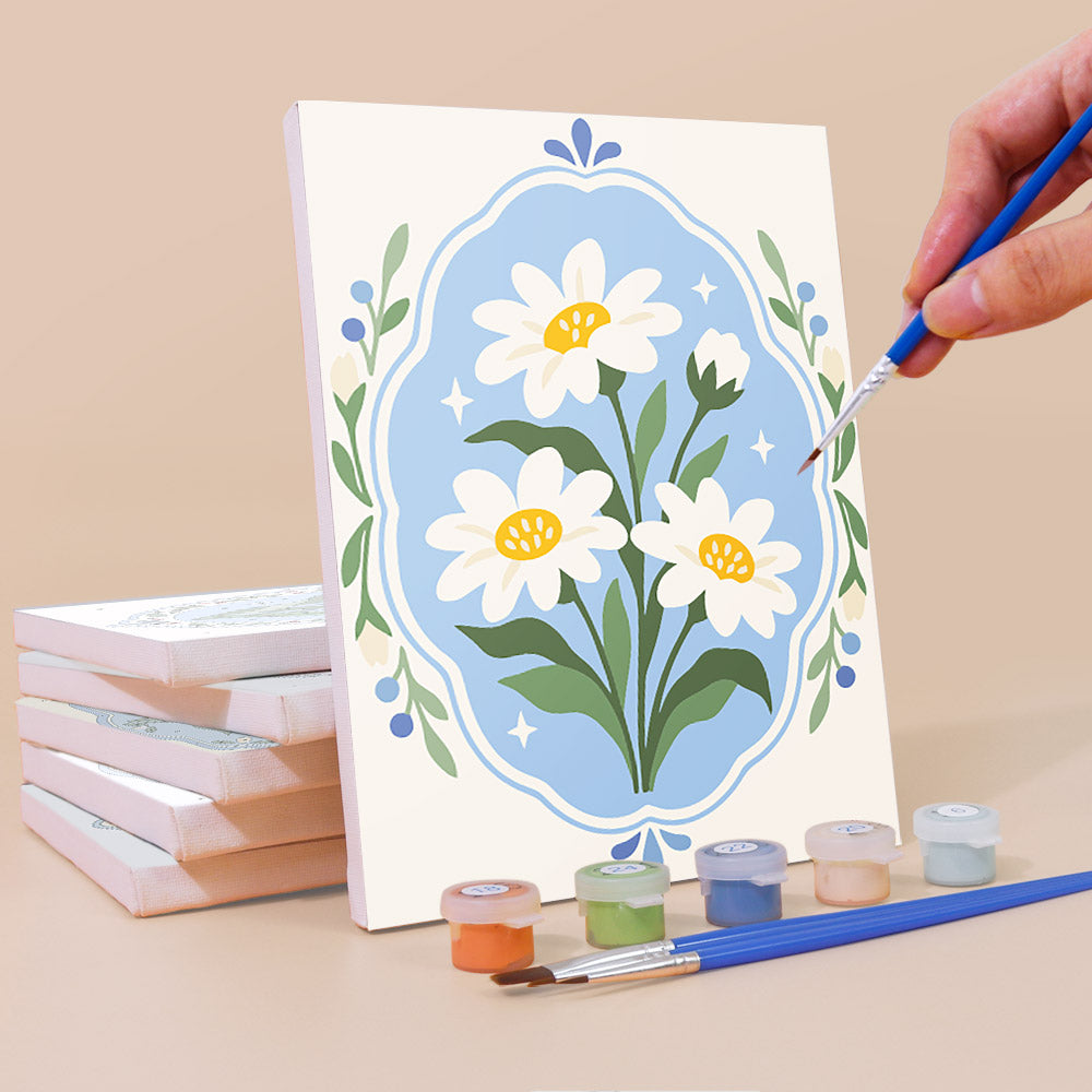Painting a Blue Folk Florals mini canvas propped up beside numbered acrylic paints