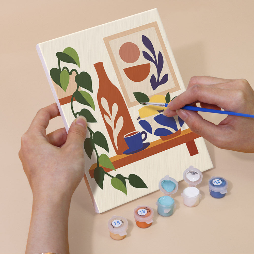 Hand holding a Boho Tea Time mini canvas while painting the details