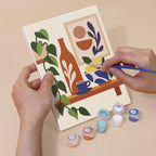 Hand holding a Boho Tea Time mini canvas while painting the details