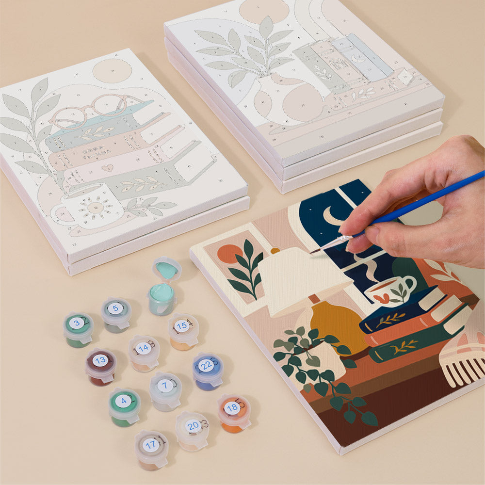 Painting one of the Book Lover's Corner designs next to a stack of mini canvases
