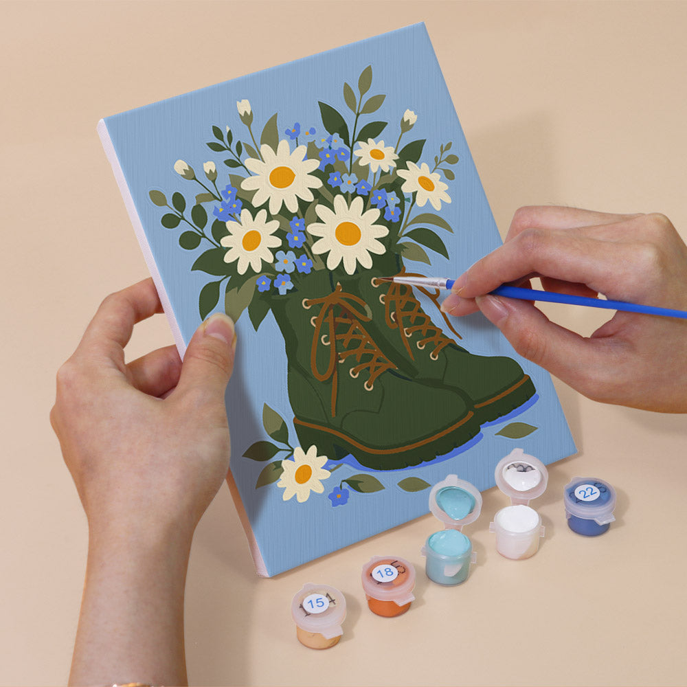 Hand holding a Boot Bouquets mini canvas while painting the details