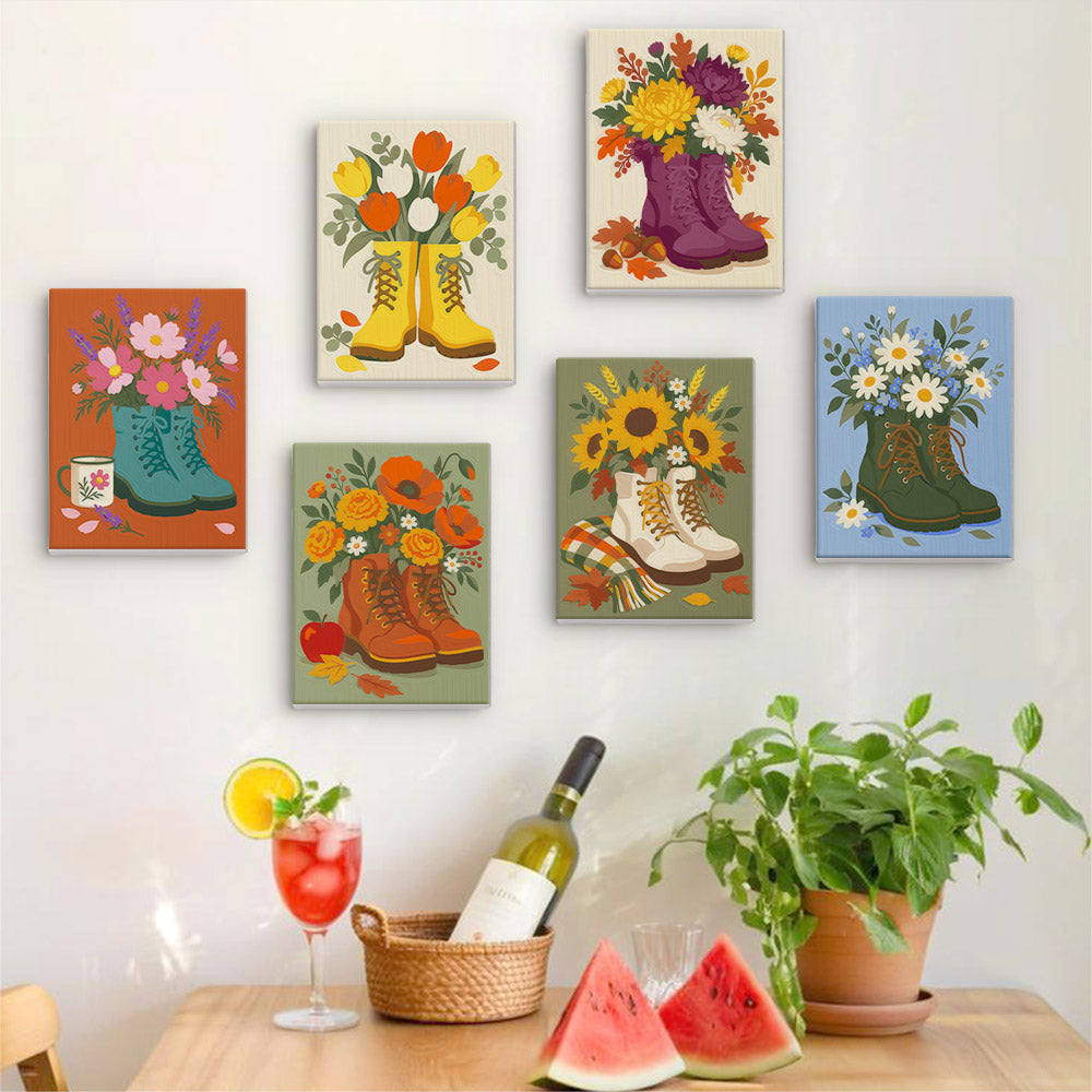 Six finished Boot Bouquets mini paintings hung on a wall above a table