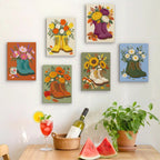 Six finished Boot Bouquets mini paintings hung on a wall above a table