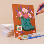Painting a Boot Bouquets mini canvas propped up beside numbered acrylic paints