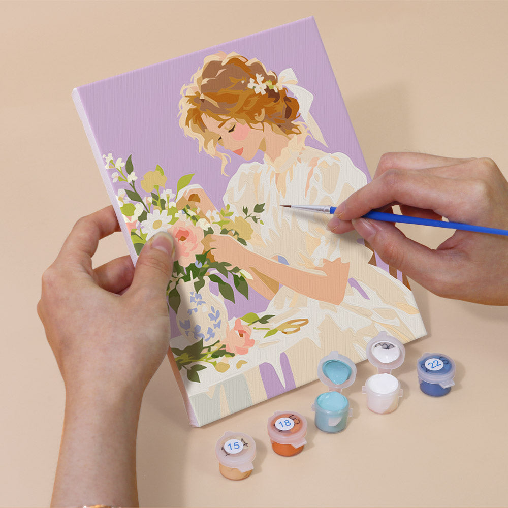 Hand holding a Bouquet Belles mini canvas while painting the details