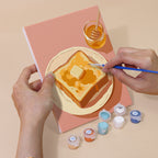 Hand holding a Brunch Club mini canvas while painting the details