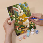 Hand holding a Bunny Garden mini canvas while painting the details