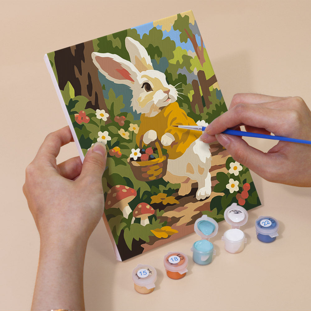 Hand holding a Bunny Garden mini canvas while painting the details
