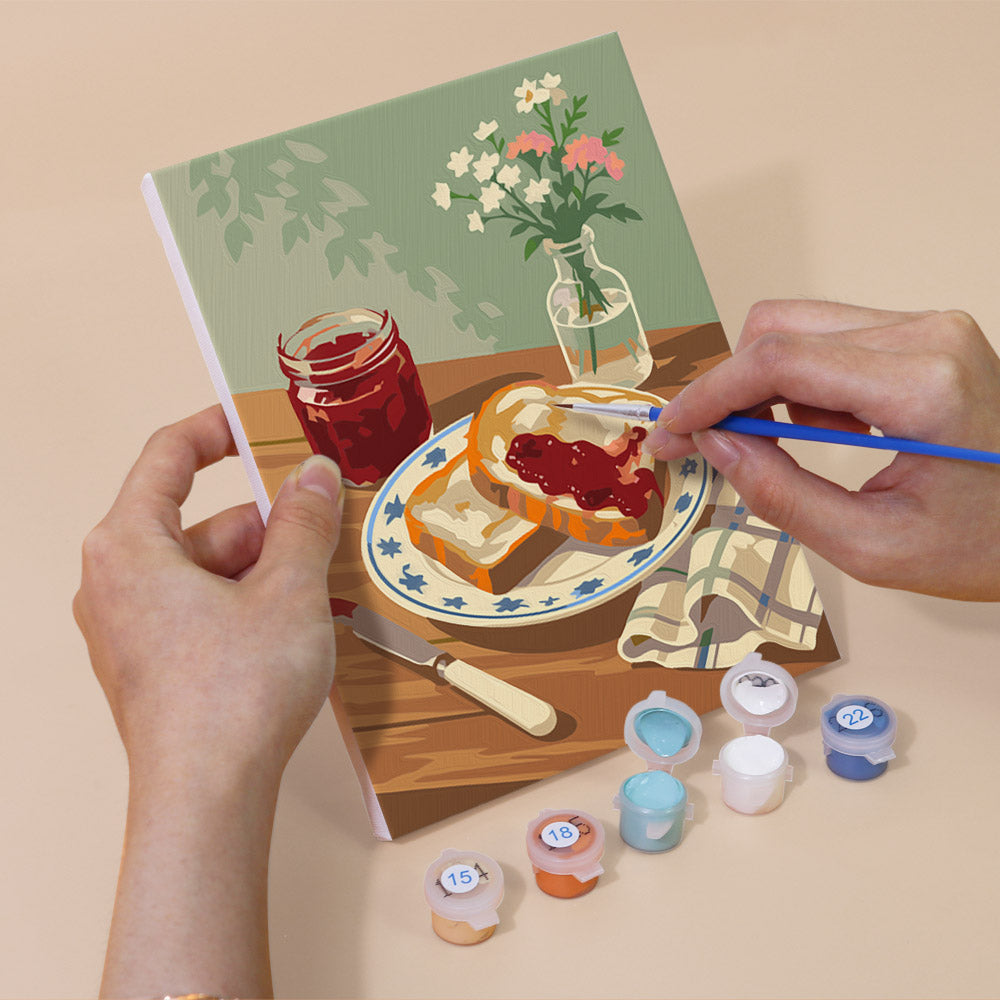 Hand holding a Café Mornings mini canvas while painting the details