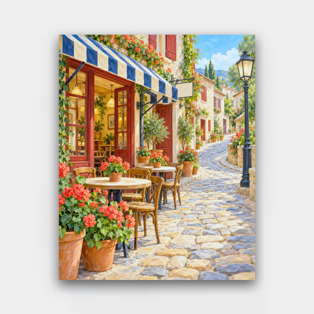 Cafe on the Hill paint by numbers kit of a cafe with striped awnings, red geraniums and bistro tables along a winding cobbled street