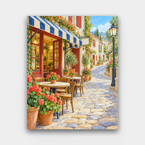 Cafe on the Hill paint by numbers kit of a cafe with striped awnings, red geraniums and bistro tables along a winding cobbled street