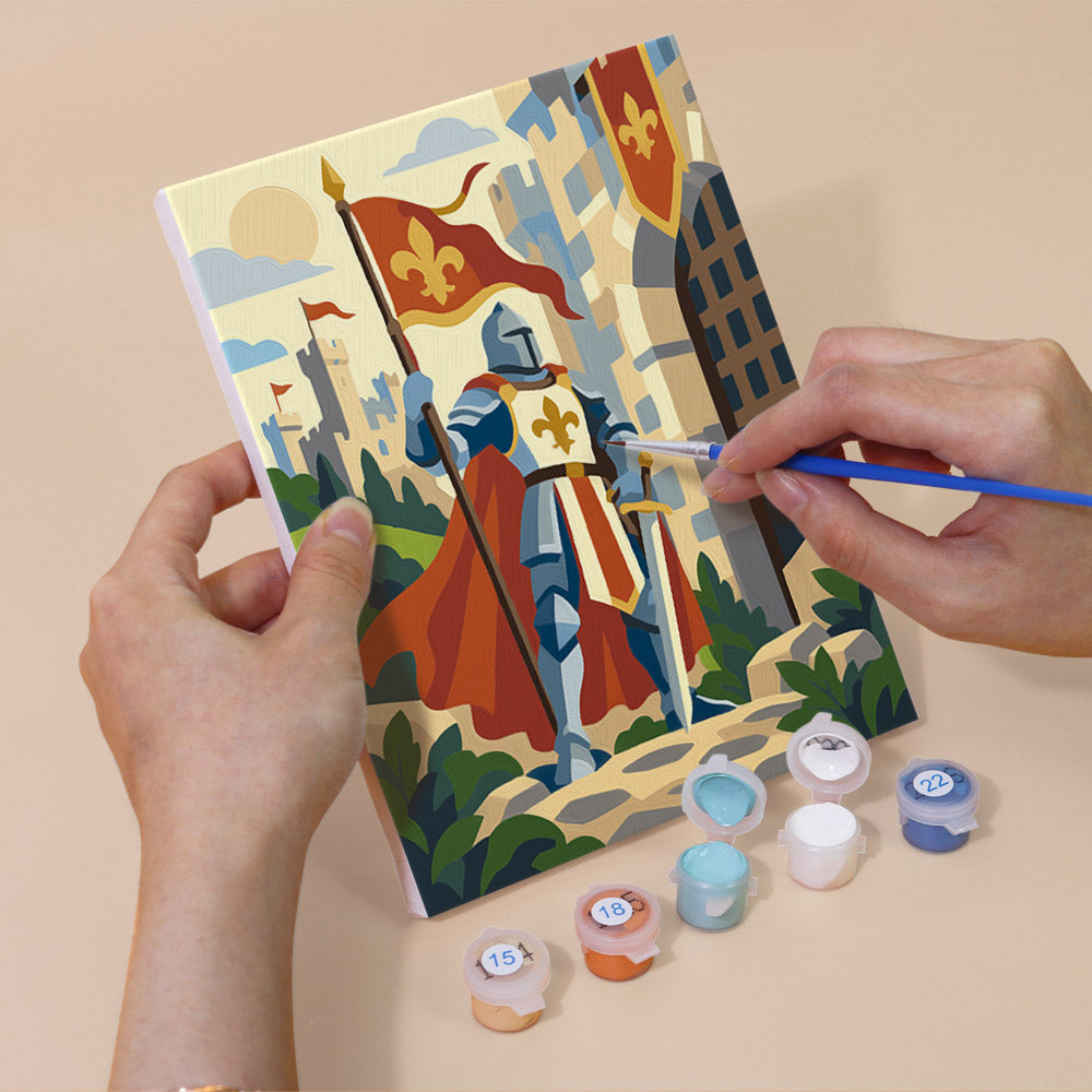 Hand holding a Castles & Knights mini canvas while painting the details