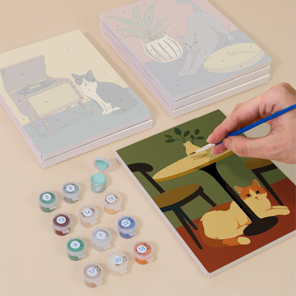 Painting one of the Cats at Home designs next to a stack of mini canvases