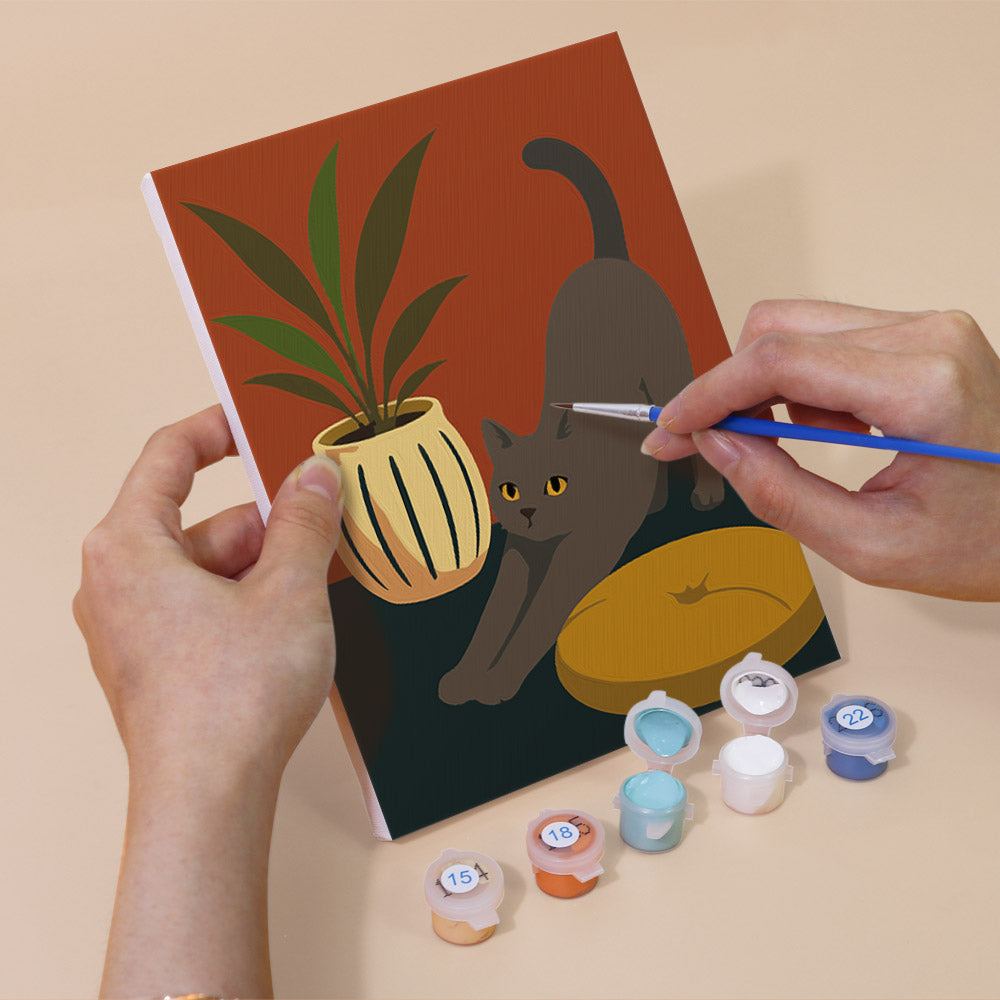 Hand holding a Cats at Home mini canvas while painting the details