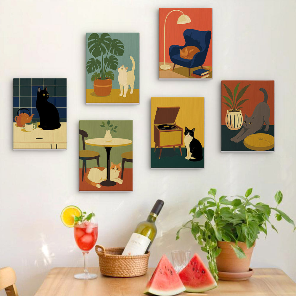 Six finished Cats at Home mini paintings hung on a wall above a table