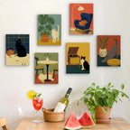 Six finished Cats at Home mini paintings hung on a wall above a table