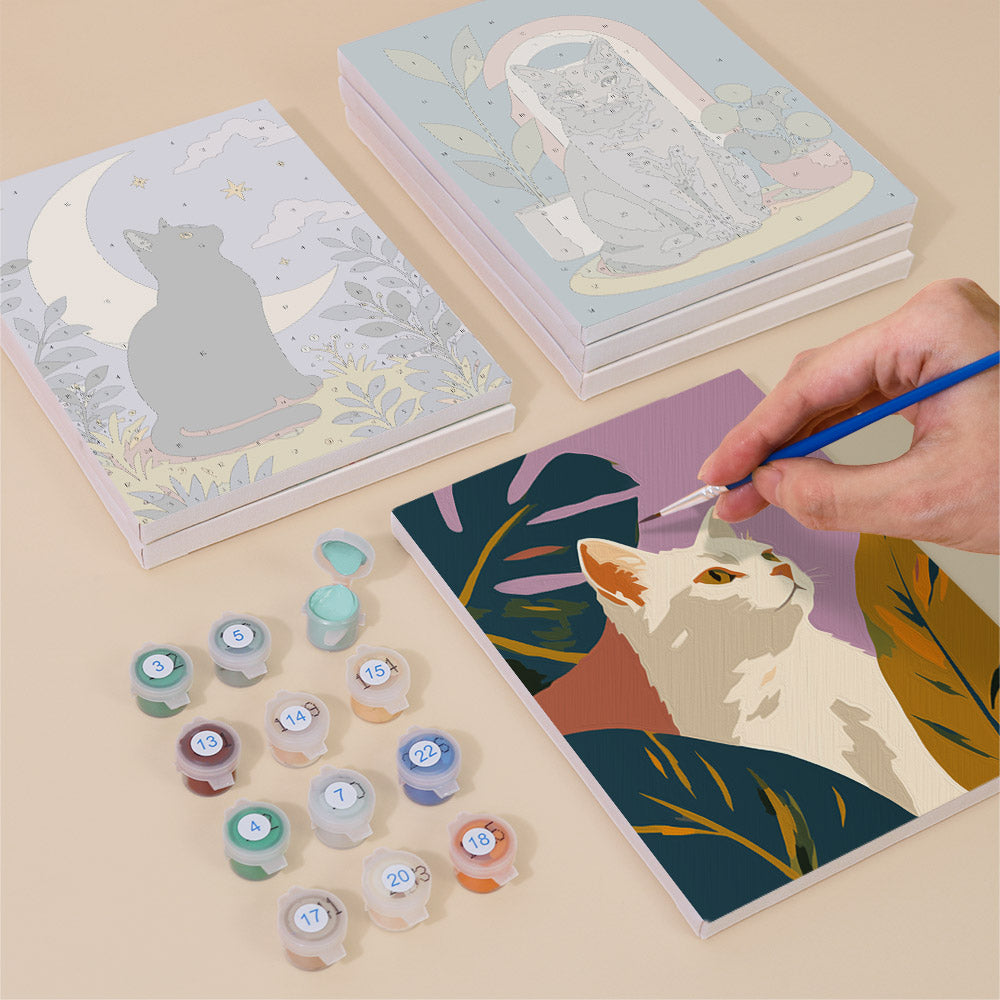 Painting one of the Cats Through the Seasons designs next to a stack of mini canvases