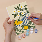 Hand holding a Checkerboard Still Life mini canvas while painting the details