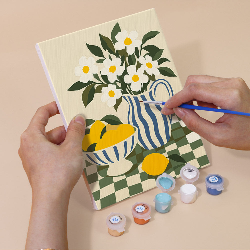Hand holding a Checkerboard Still Life mini canvas while painting the details