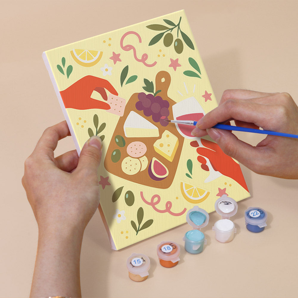Hand holding a Cheers and Treats mini canvas while painting the details