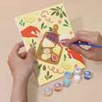 Hand holding a Cheers and Treats mini canvas while painting the details
