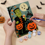 Hand holding a Classic Monster Moon mini canvas while painting the details