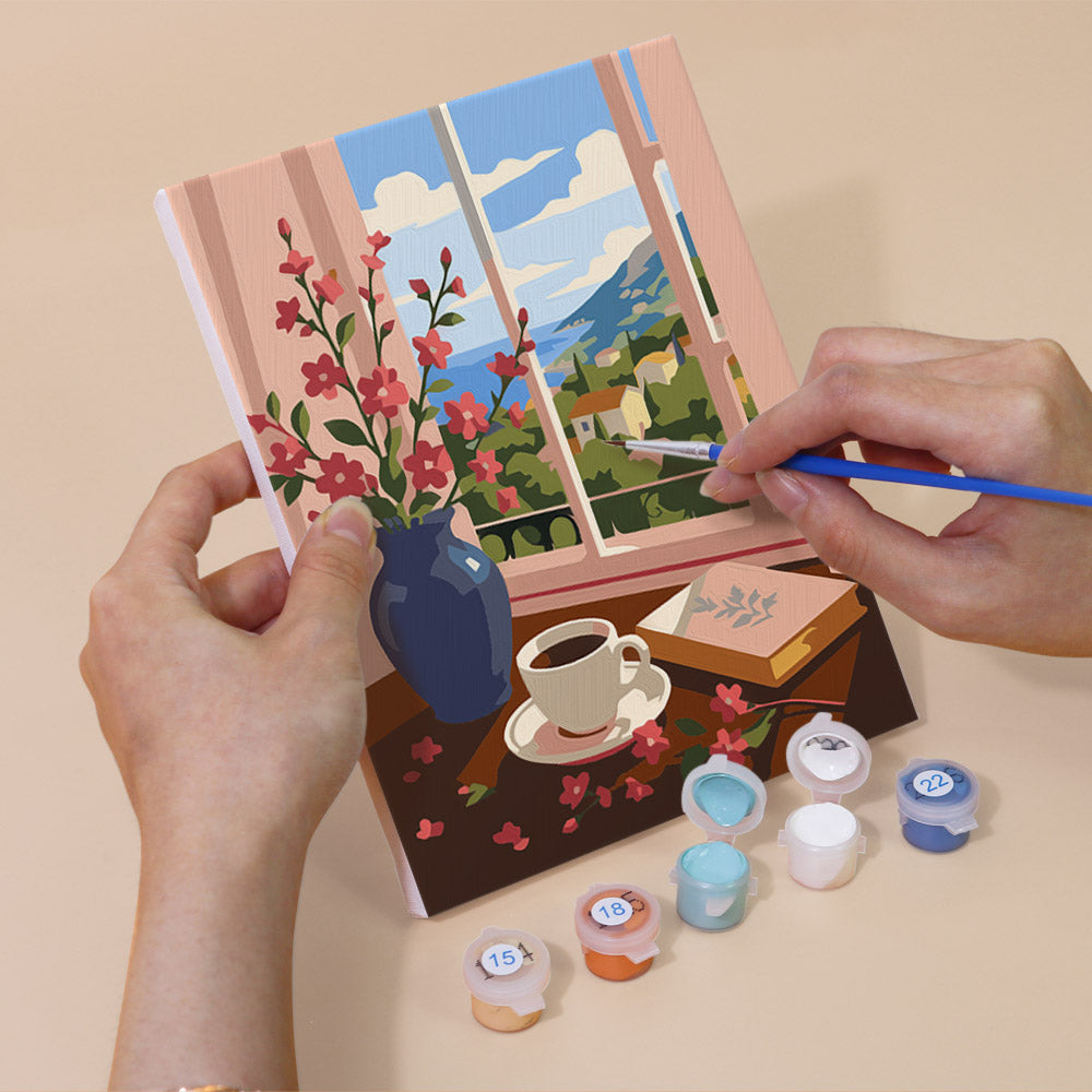 Hand holding a Coastal Breakfast mini canvas while painting the details