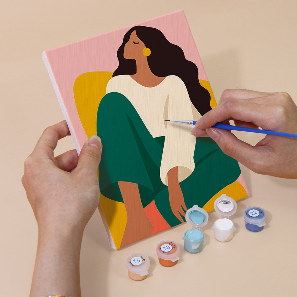 Hand holding a Color Block Ladies mini canvas while painting the details